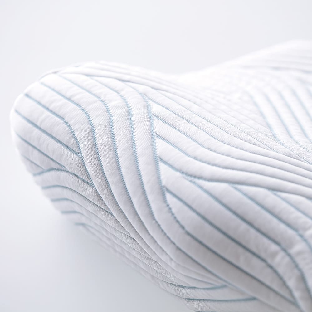 Hvid ergonomisk pude med et blåt stribet quiltet mønster.