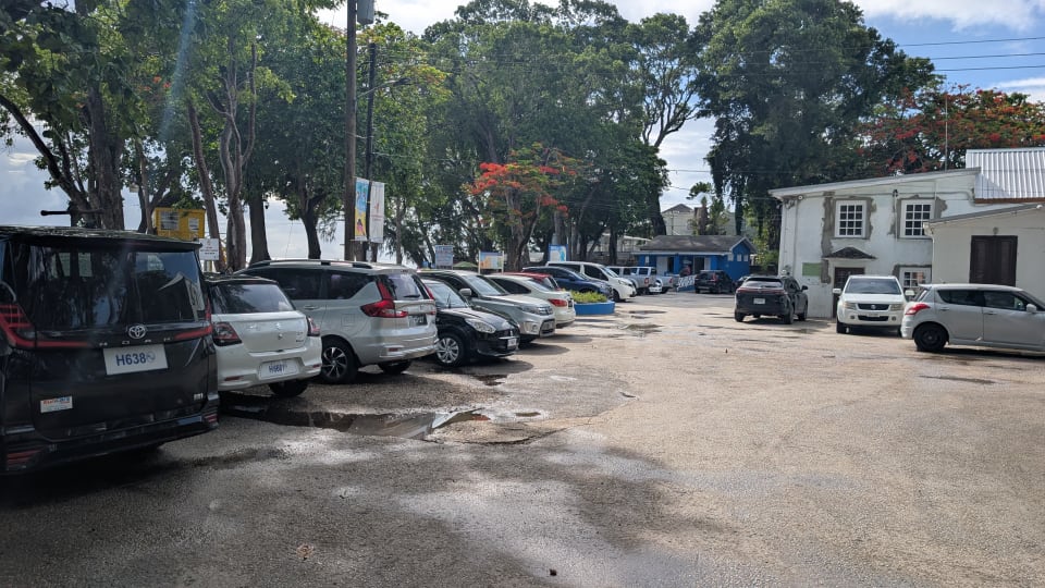 Parking lot with vehicles near the entrance to Folkestone Beach in St. James, Barbados.