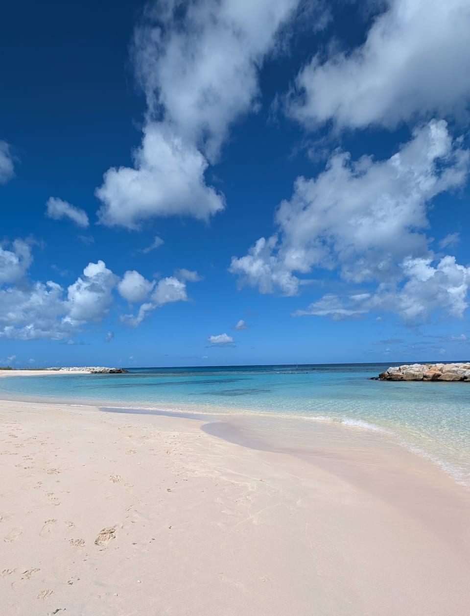 Wide sandy shoreline and calm turquoise water at Heywoods Beach on the west coast of Barbados beneath a bright blue sky.