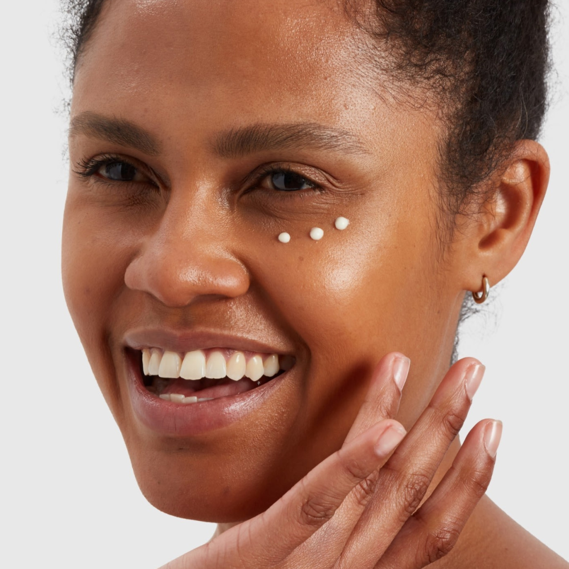 Smiling woman with three dots of product under her eye