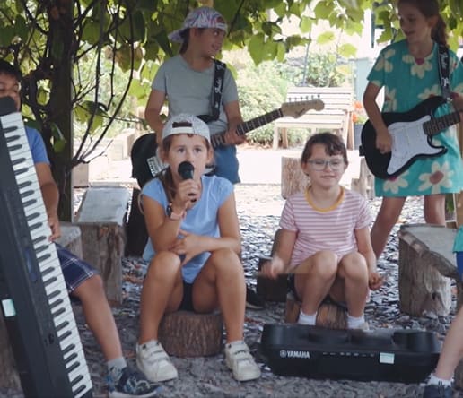 irock summer camp band with student holding microphone