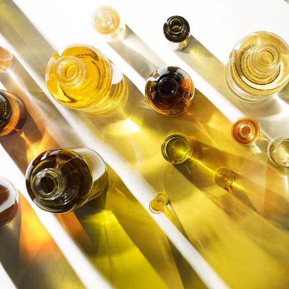 Top-down view of assorted amber and golden glass bottles casting long diagonal shadows on a white surface.