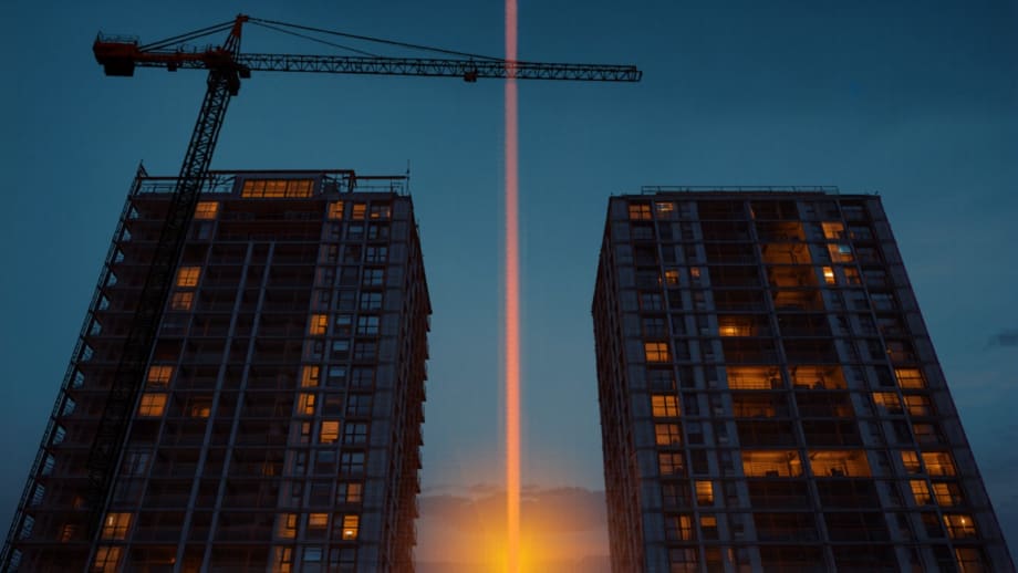 Edificio en construcción junto a uno terminado con ventanas encendidas