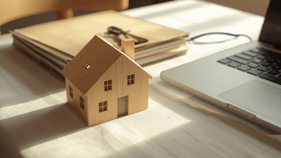 Carpeta familiar con documentos junto a casita de madera y portátil cerrado