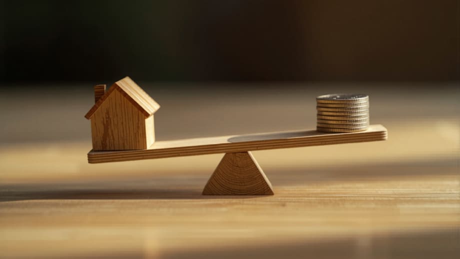 Sube y baja de madera con una casita en un extremo y monedas en el otro
