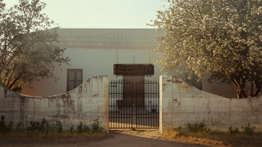 Casa de adobe entre frutales con un cartel de madera en blanco en la entrada