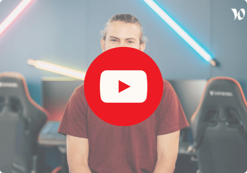 Olivier portant un t-shirt rouge, assis devant des fauteuils gaming avec un fond de néons colorés bleu et jaune. Un grand logo YouTube rouge est superposé au centre de l'image, suggérant un lien vers une vidéo.