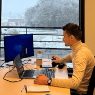 Collaborateur concentré sur deux écrans dans un bureau Extia, avec vue sur un paysage enneigé à travers une grande baie vitrée.