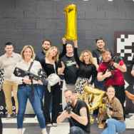 Photo d’équipe après une session de laser game : groupe de collaborateurs Extia armés de pistolets laser et ballon doré en forme de “1”.