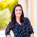 Retrato de Sonia, una mujer sonriente de cabello castaño, vestida con una blusa azul marino con estampados blancos. Posó en el exterior con un fondo luminoso y verde.