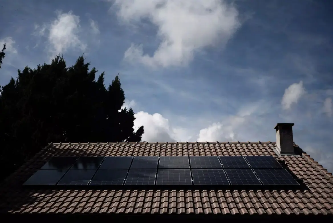 Telhado residencial com painéis solares e sombra de árvore
