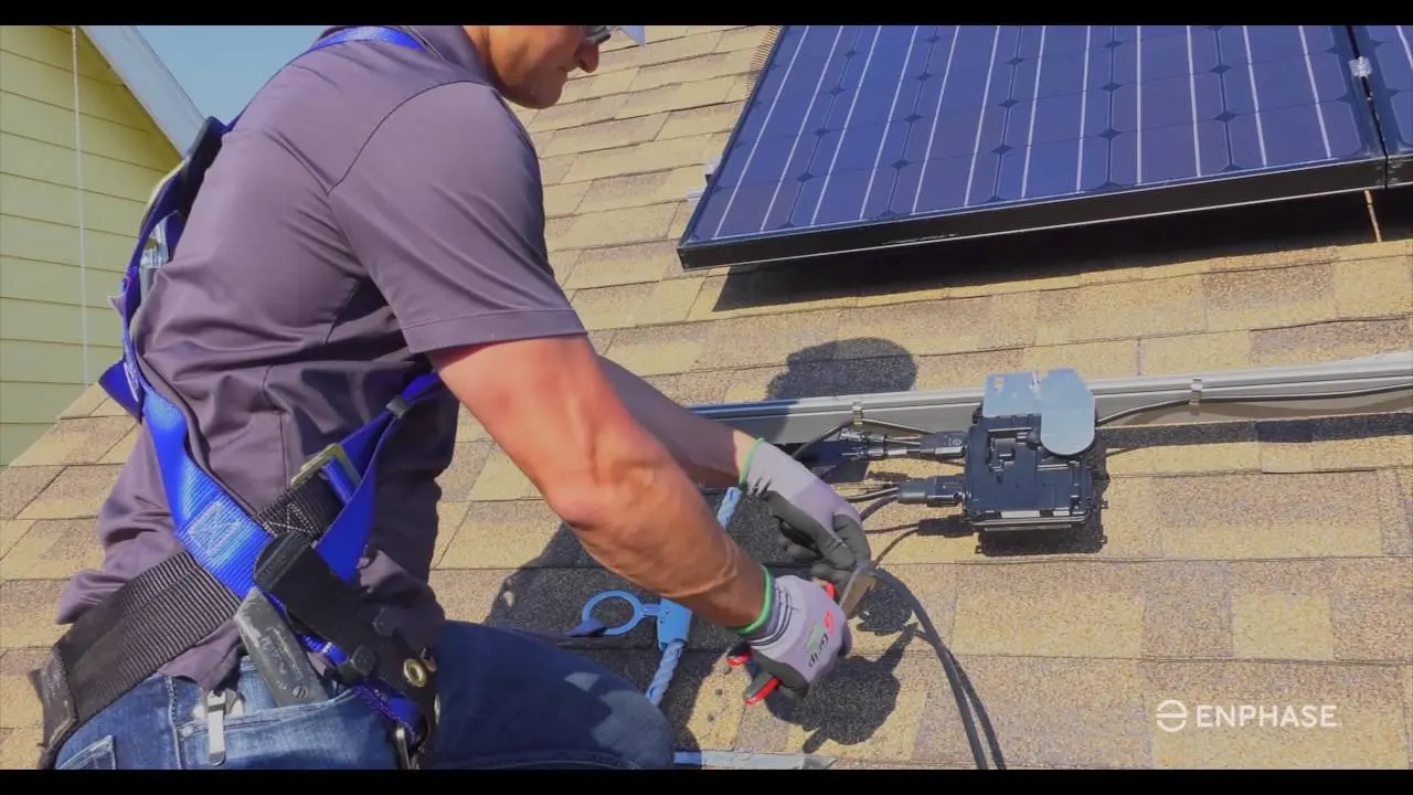 Técnico instalando microinversor Enphase sob painel solar