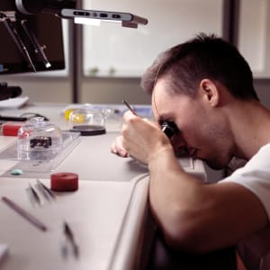 Watchmaker inspecting a part with a magnifying glass