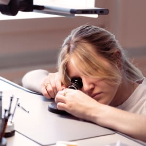 Watchmaker examining a component with a magnifying glass