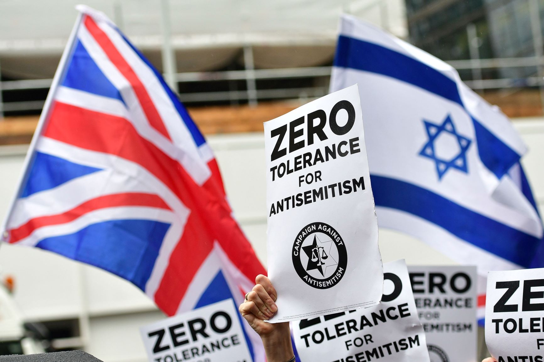 Signs reading 'Zero tolerance for antisemitism' in front of the Israeli and Union flag Signs reading 'Zero tolerance for antisemitism' in front of the Israeli and Union flag