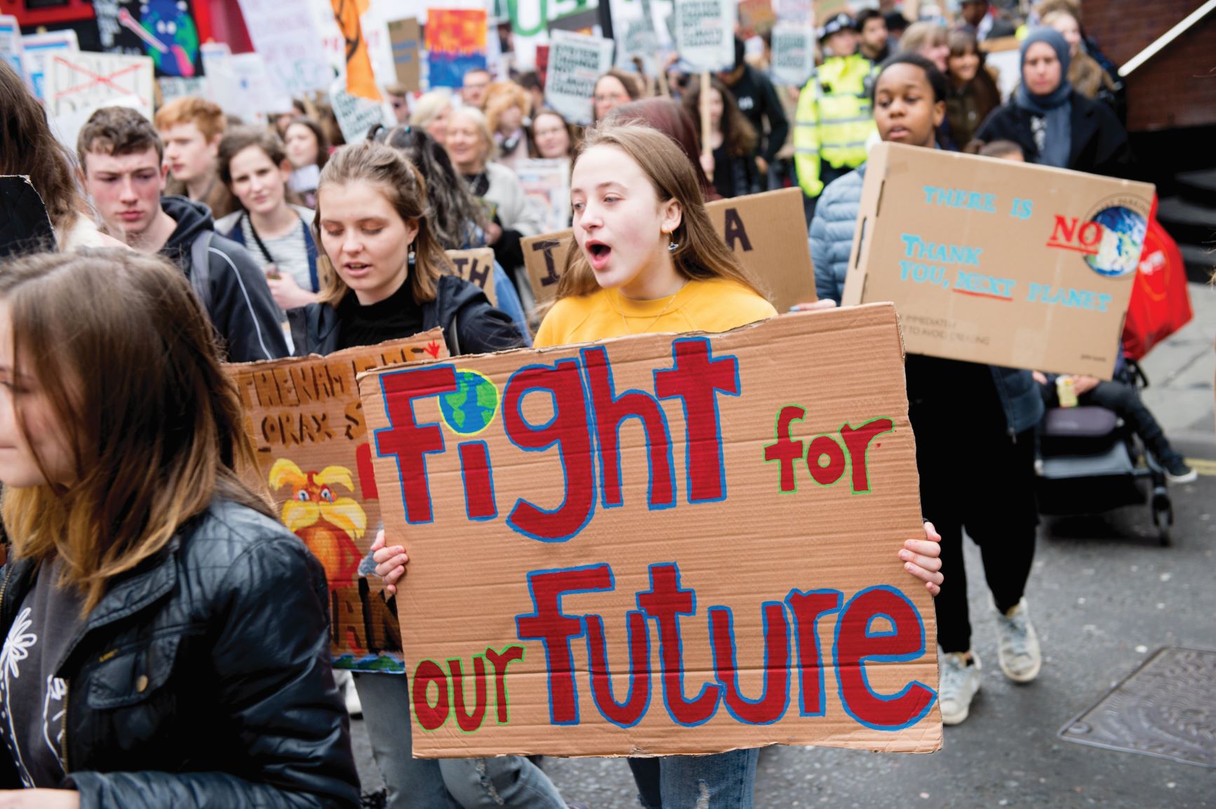 YouthStrike4Climate Fridays For Future Climate Change Protest - Central London School strikers march with signs. A teenage girl with long brown hair holds a cardboard sign saying