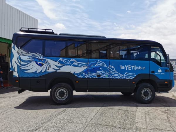 A rugged 4x4 bus driving through a vast, volcanic landscape in the Icelandic highlands