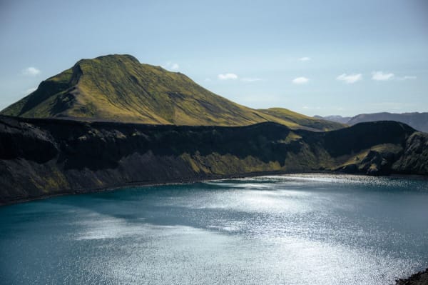Vibrant rhyolite mountains rise above a steaming geothermal stream in the Icelandic Highlands