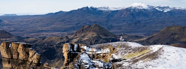 A dramatic waterfall cascades over mossy cliffs in a lush Icelandic landscape