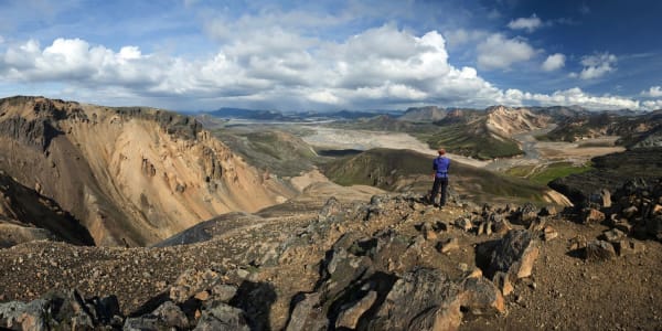 A rugged highland bus traverses a vast, volcanic landscape toward the Landmannalaugar mountains