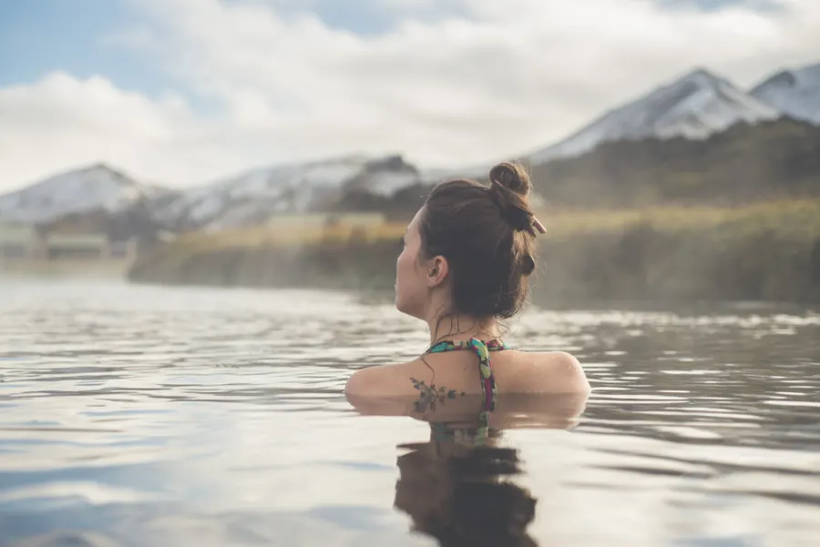 A female tourist having a nice swim in one of the best hot springs in Landmannalaugar