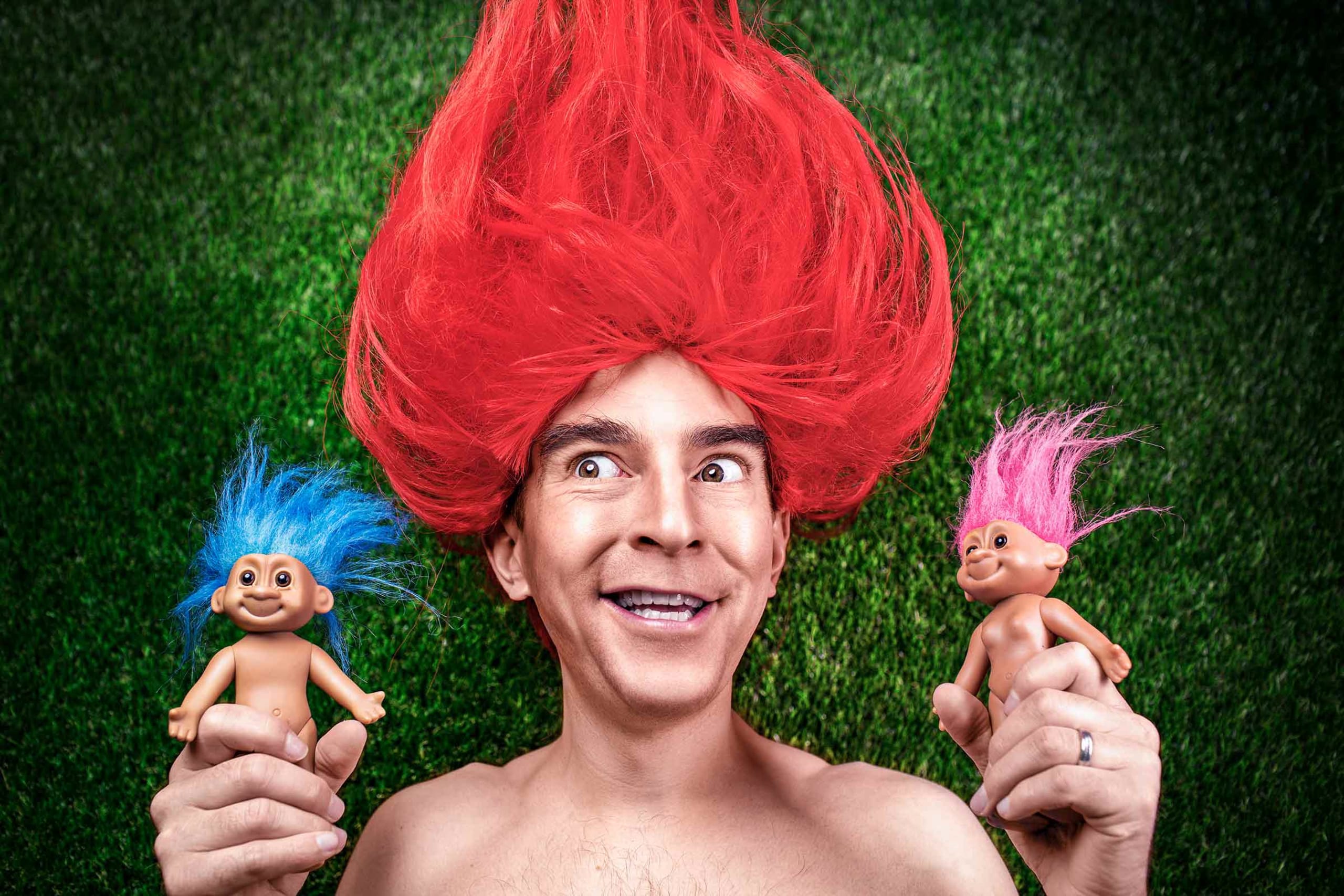 man with troll hair holding troll toys