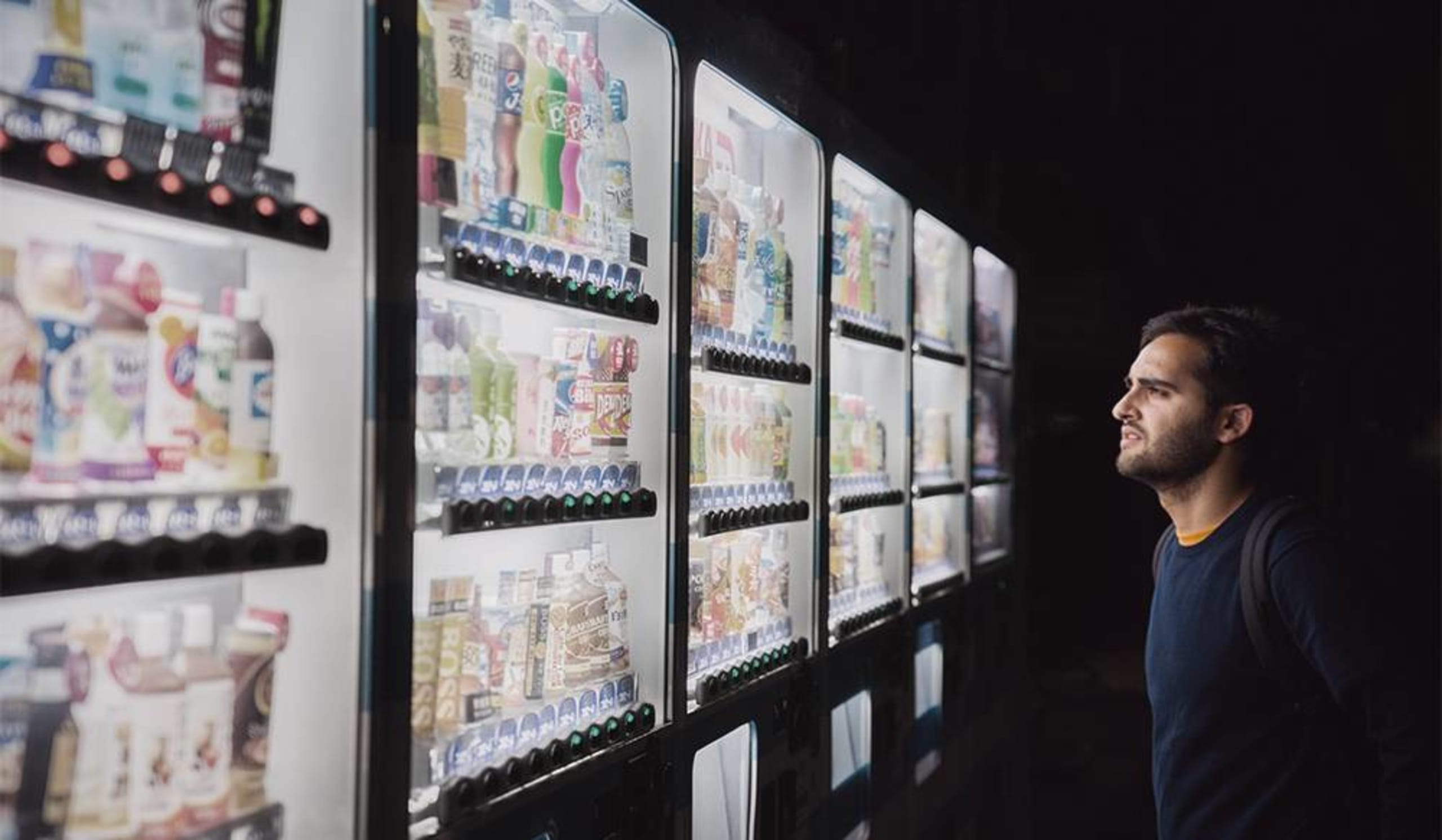 man viewing drinks from vending machines