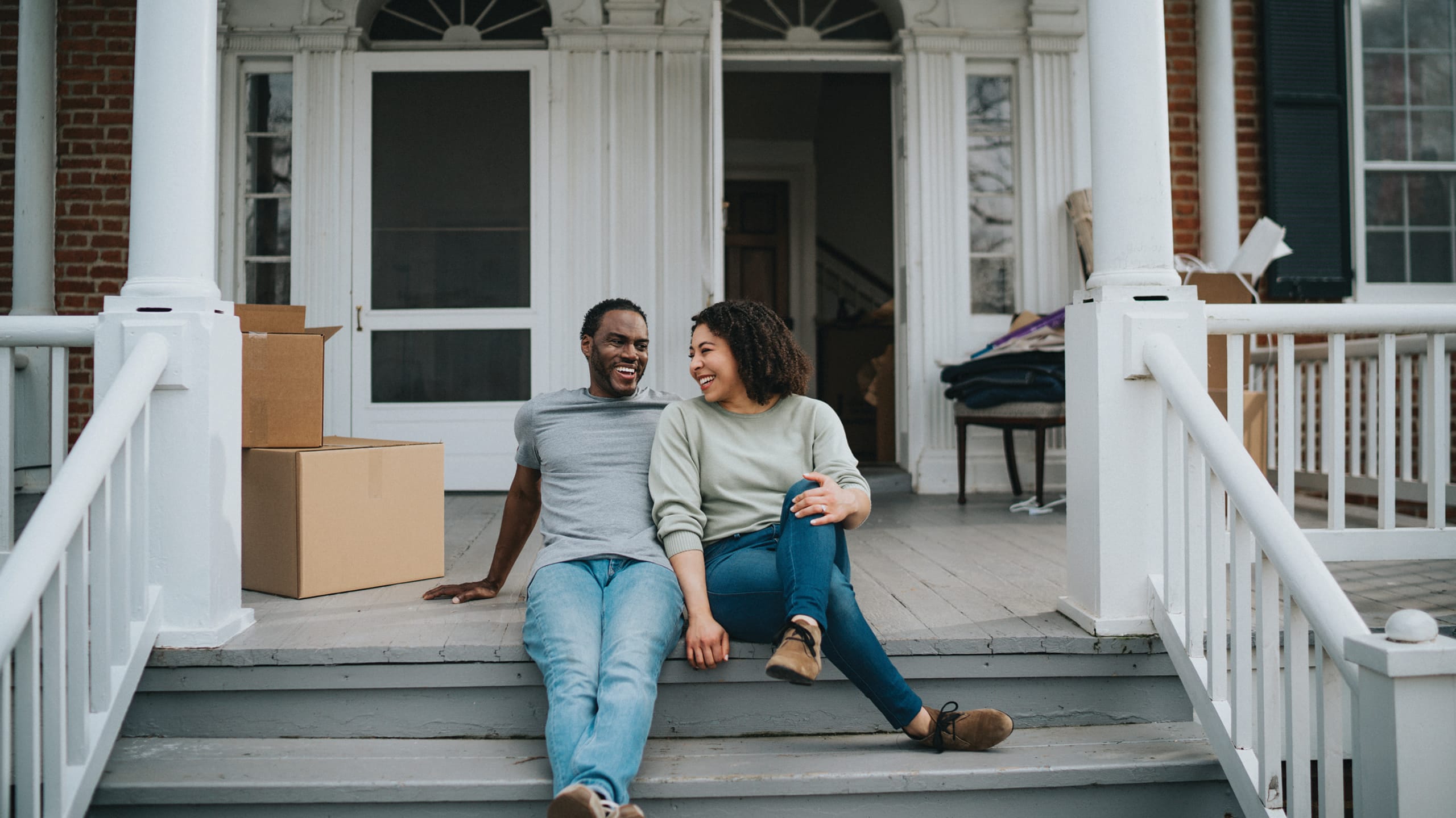a couple sitting on their front porch smiling