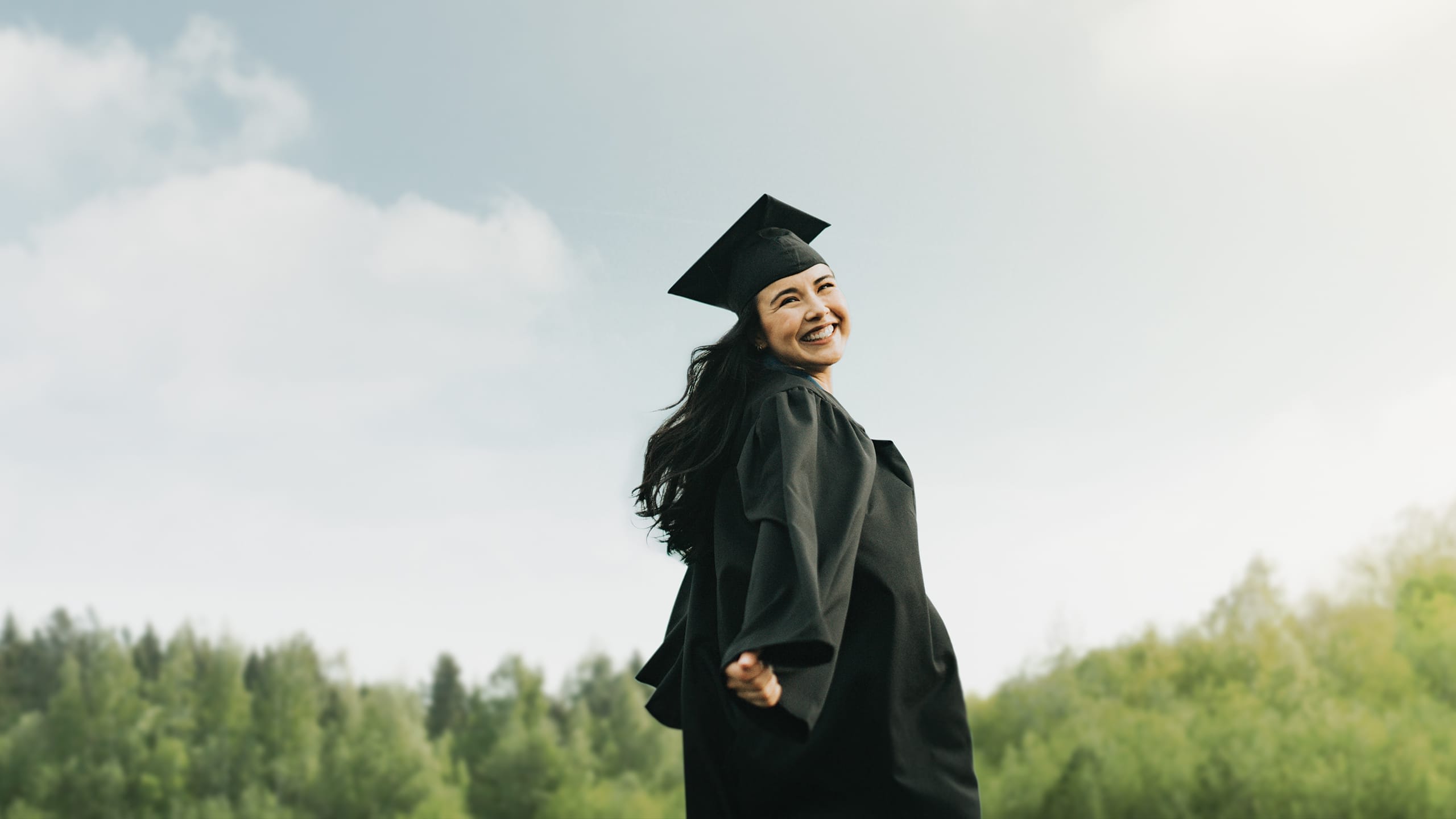 a female graduate smiling in a field
