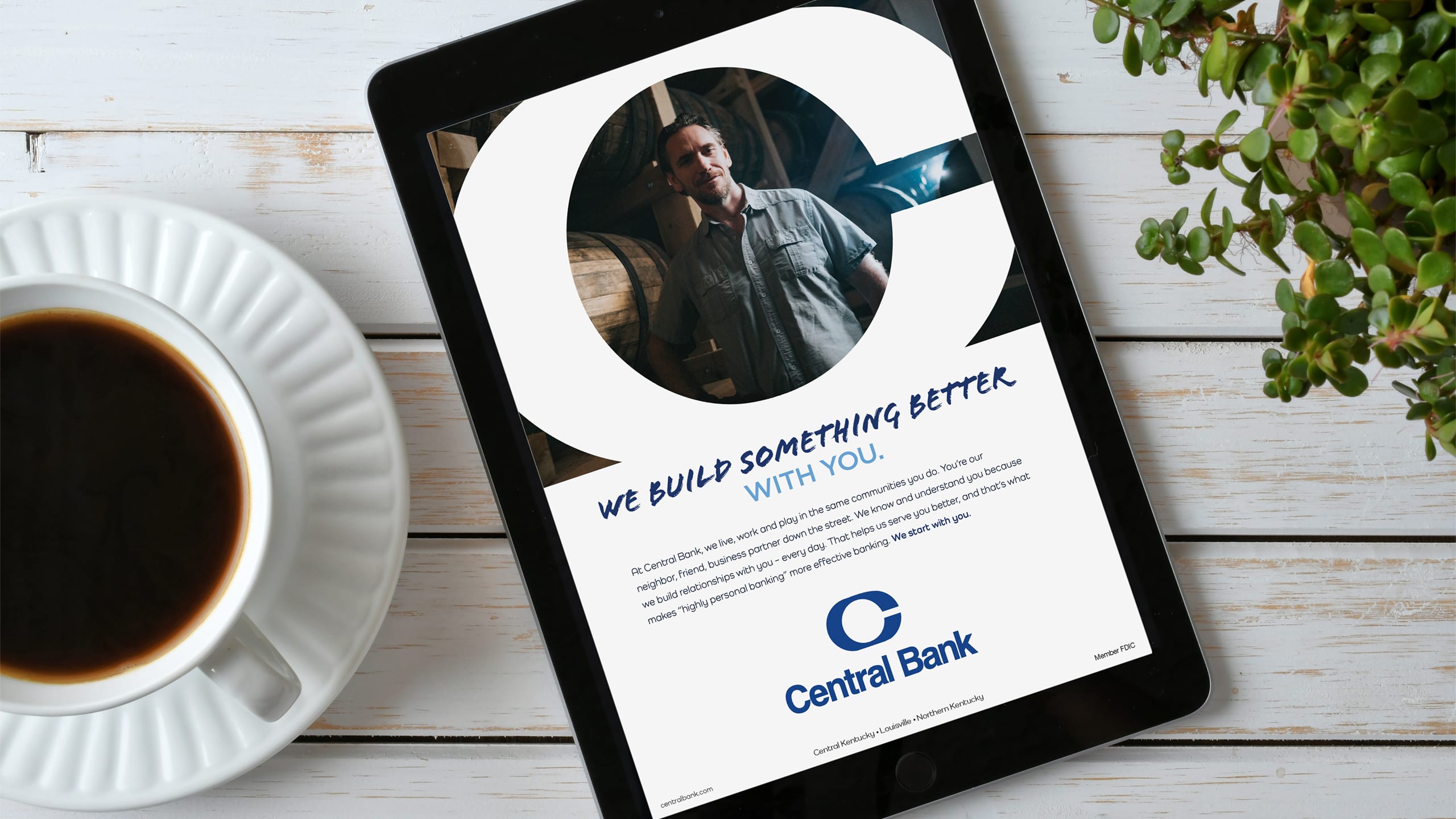 a tablet with a "we build something better with you" ad in the middle of a white wood table