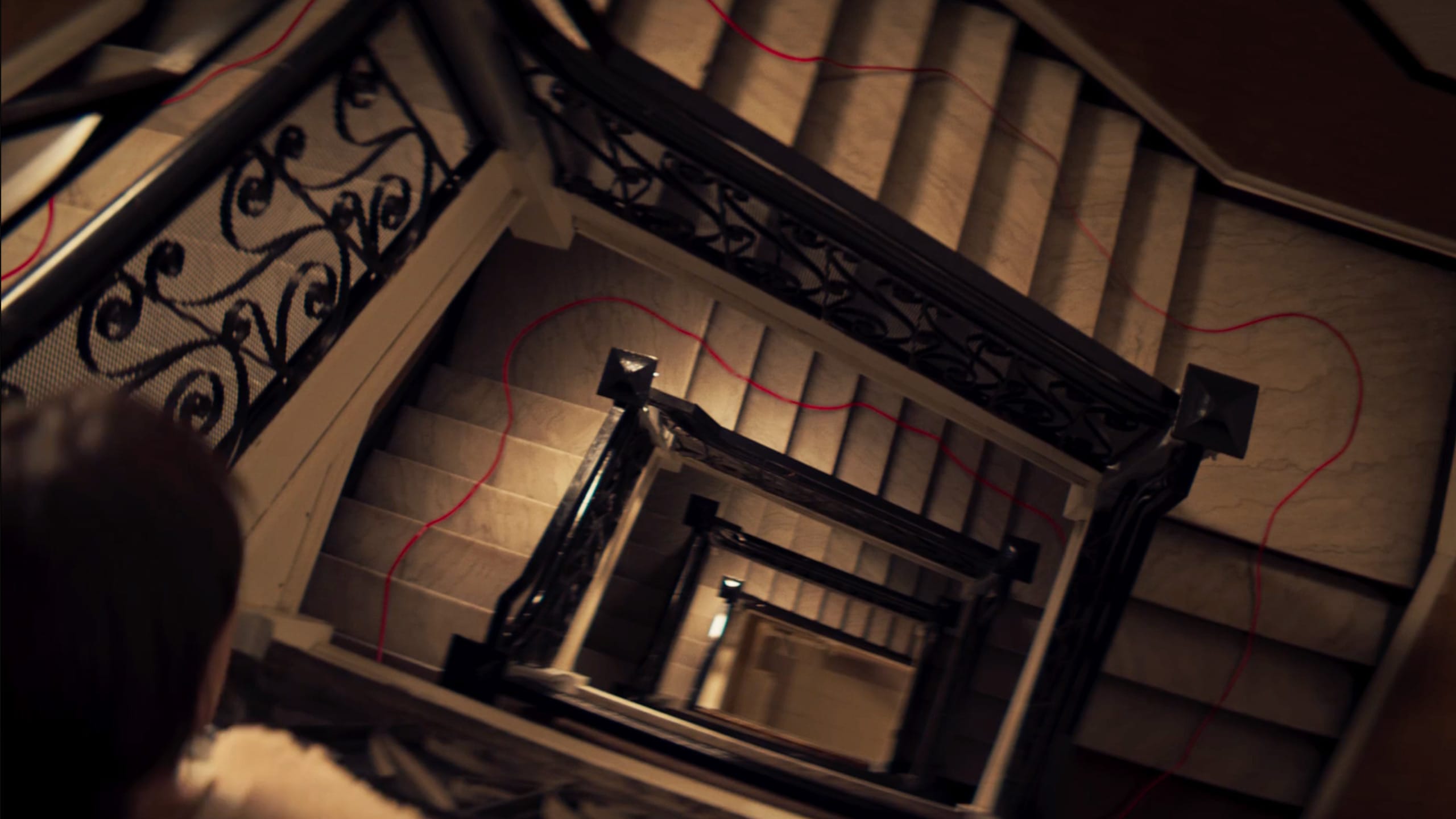 several stories of staircases with a red string guiding the way down