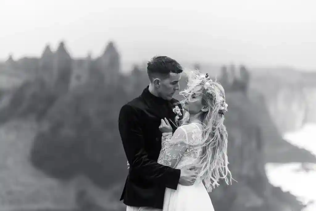 Bride and groom standing in loving embrace on cliff front NI