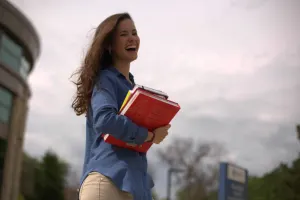 student walking with books in hand while smiling