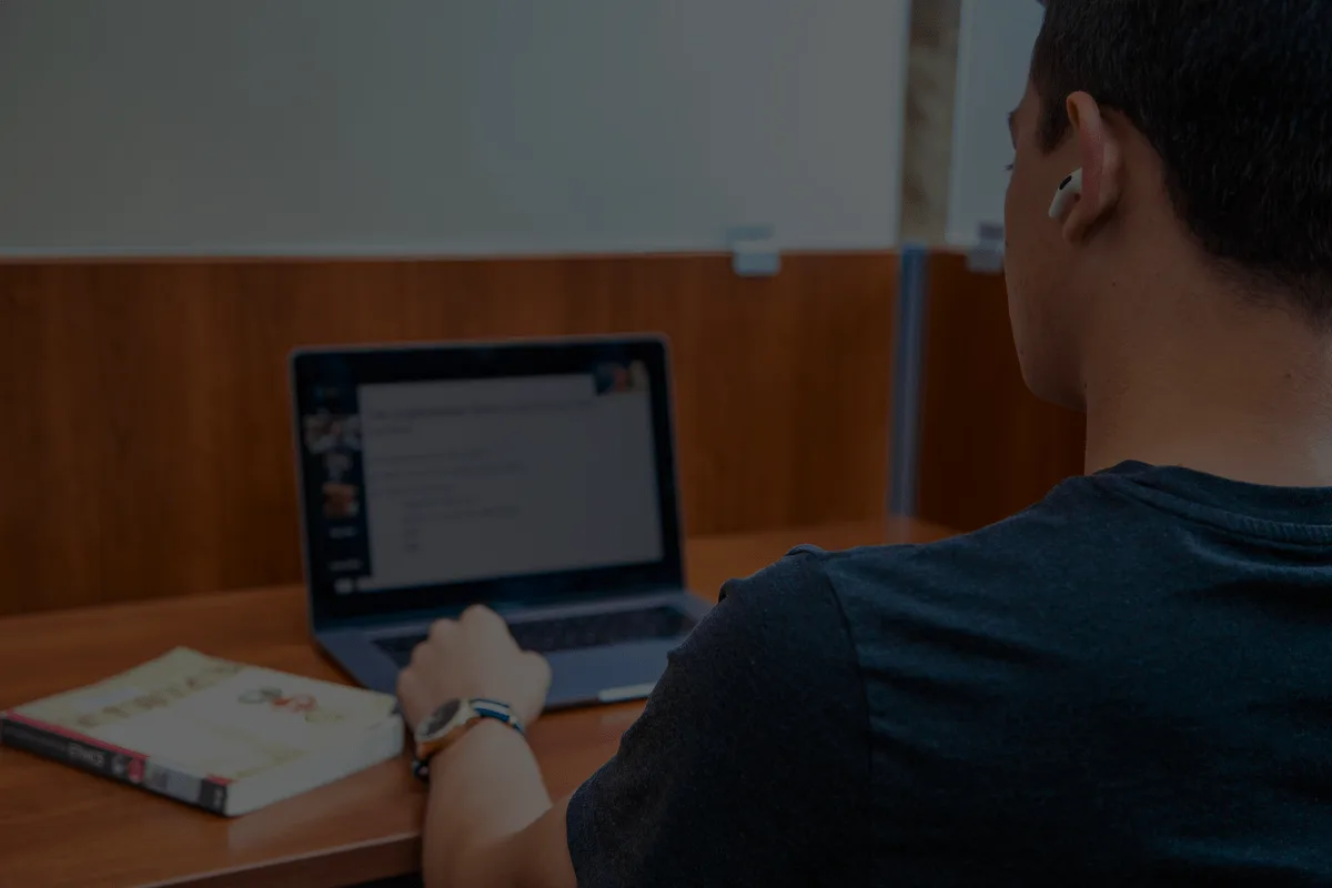 student studying in a library at their laptop