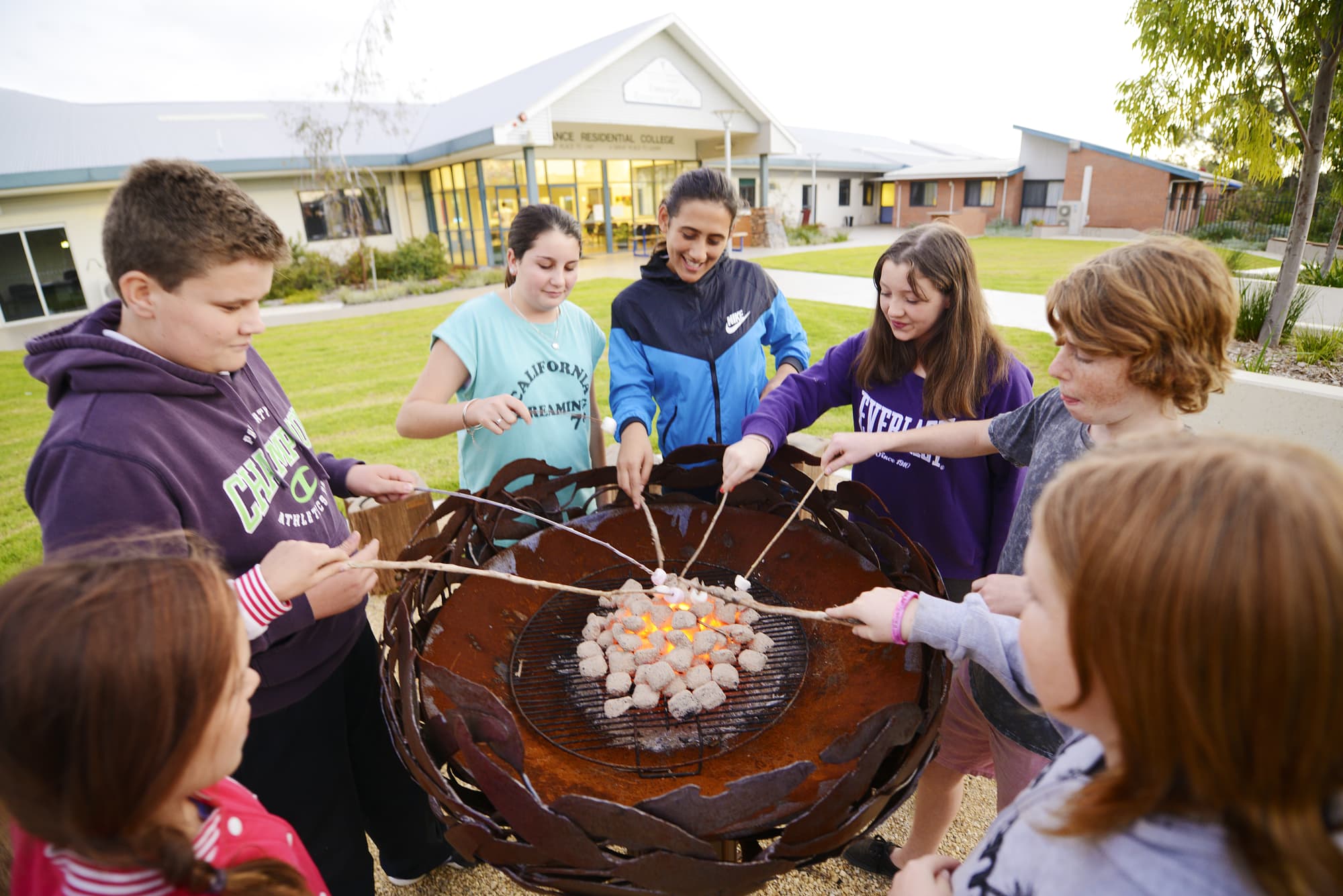 Pic of students toasting marshmallows around a fire