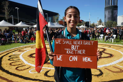 Girl holding Aboriginal flag and smiling