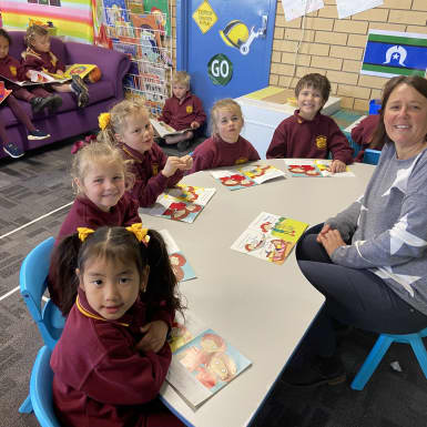 Primary school students sitting around table with teacher