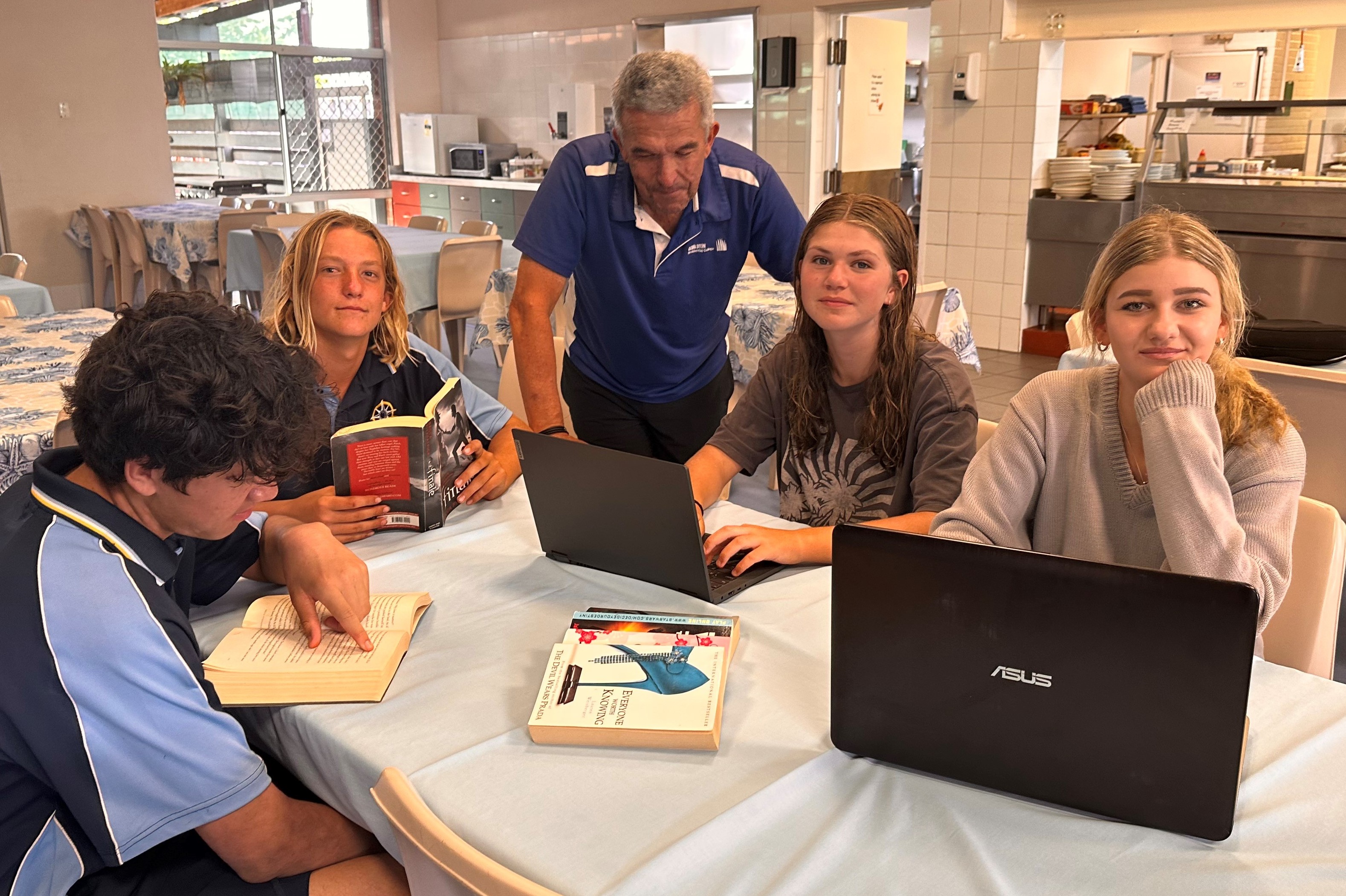 Students working together on laptops, smiling at camera