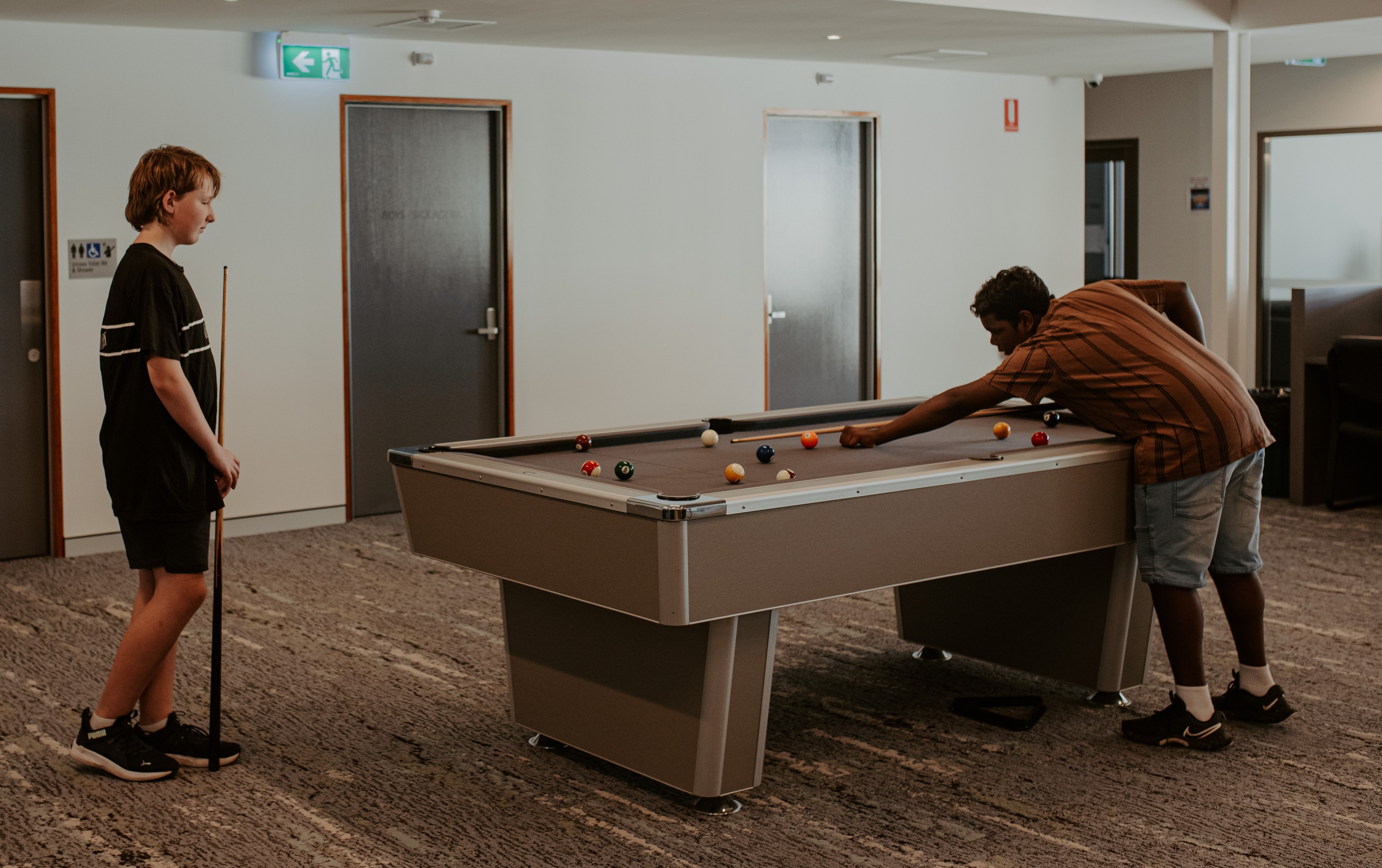 boys playing on the pool table