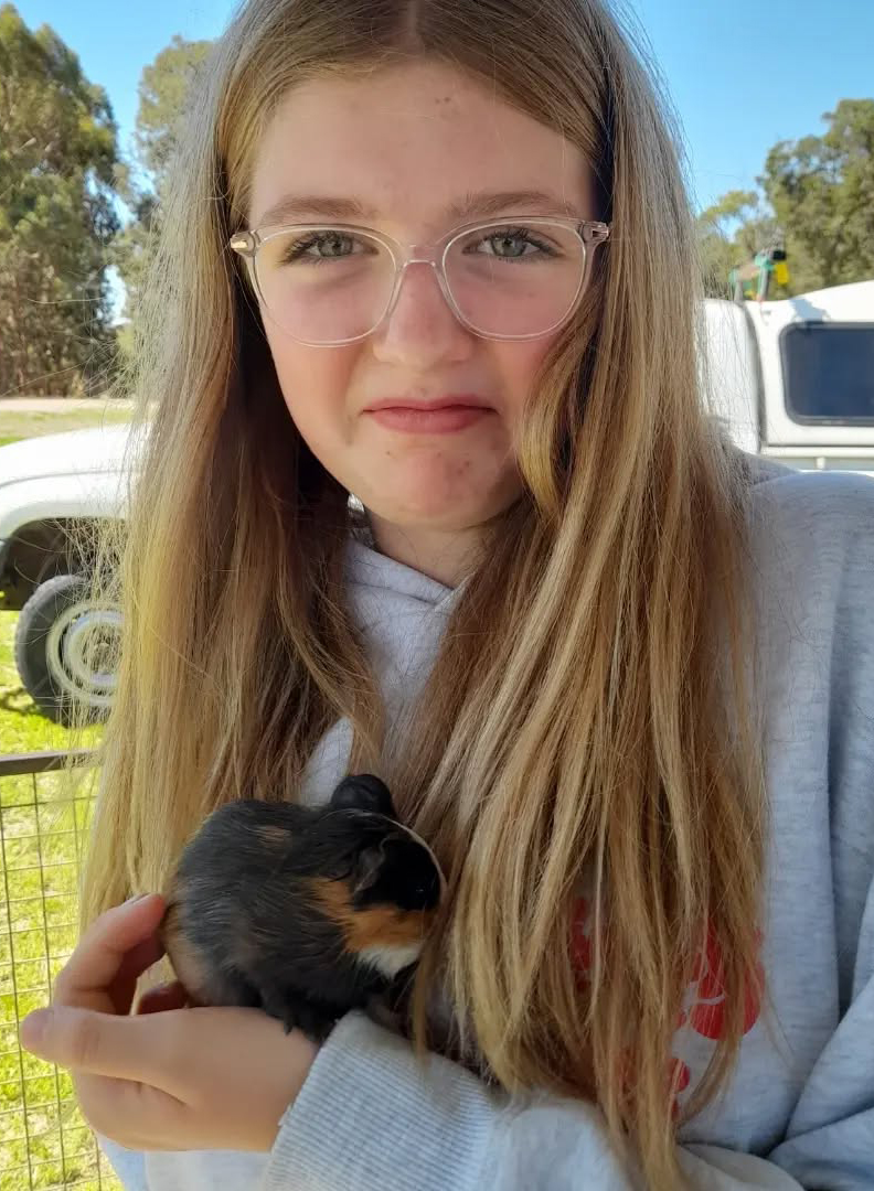 Northam Residential College boarder holding a little guinea pig at the Bakers Hill Fair