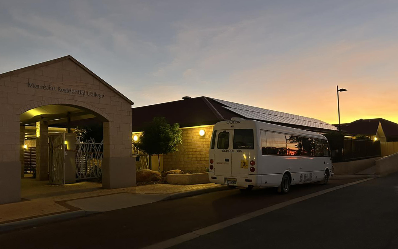The Merredin Residential College bus at the front of the college with a beautiful sunset background