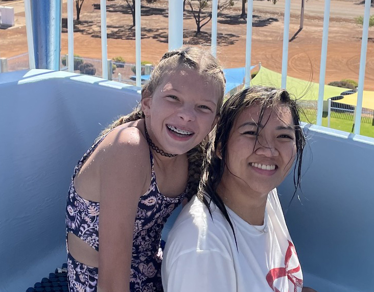 Smiling boarder from Narrogin Residential College with a boarding supervisor on a waterslide