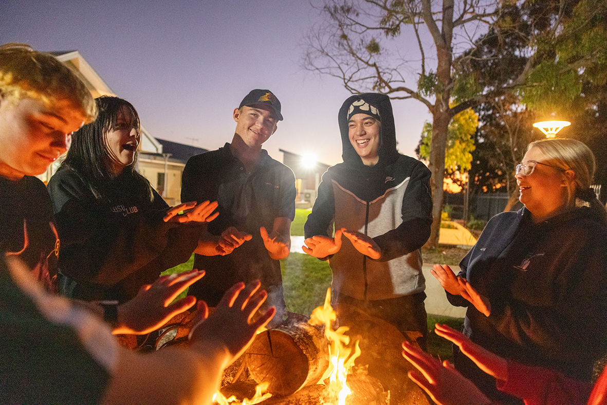 Esperance Residential Colelge boarders smiling and warming their hands around the college firepit