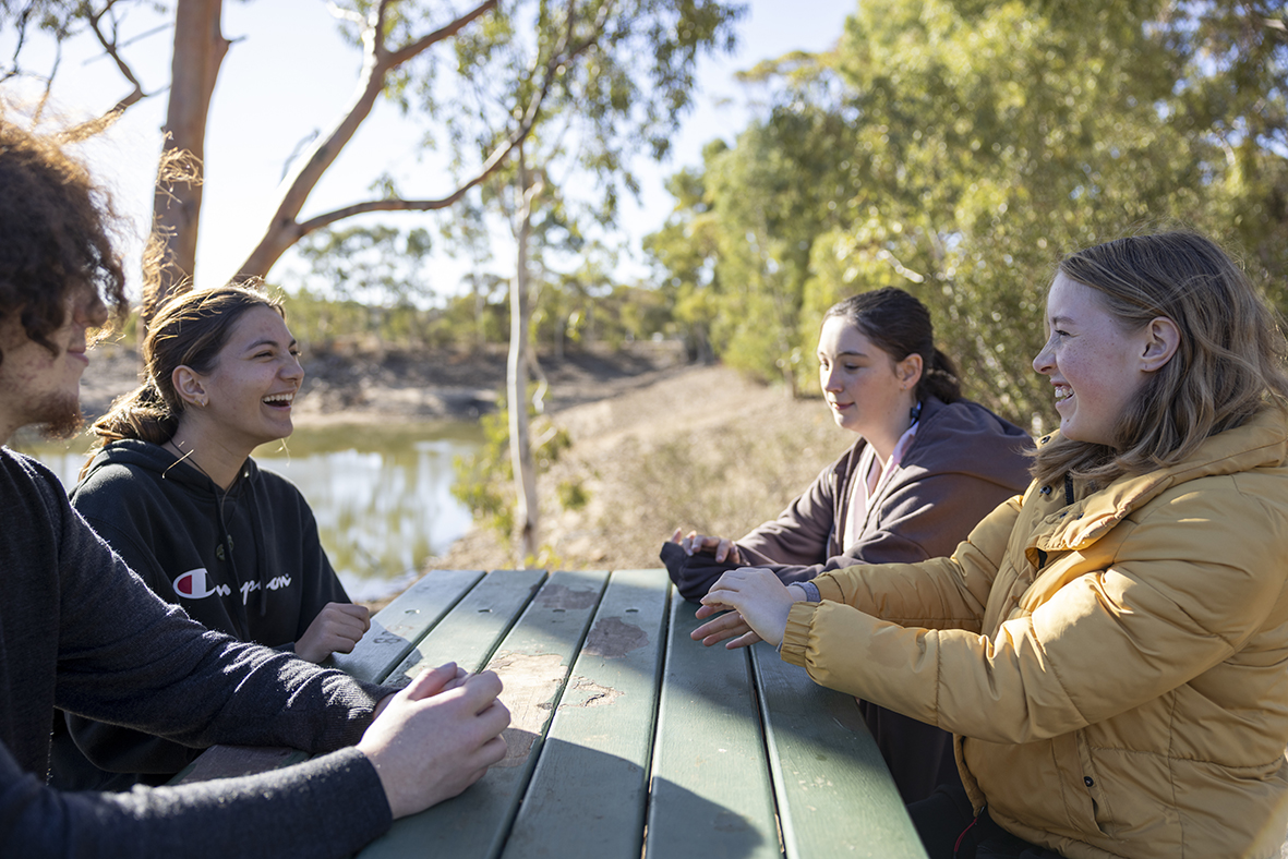 Smiling Merredin Residential College boarders sitting at a picnic table.