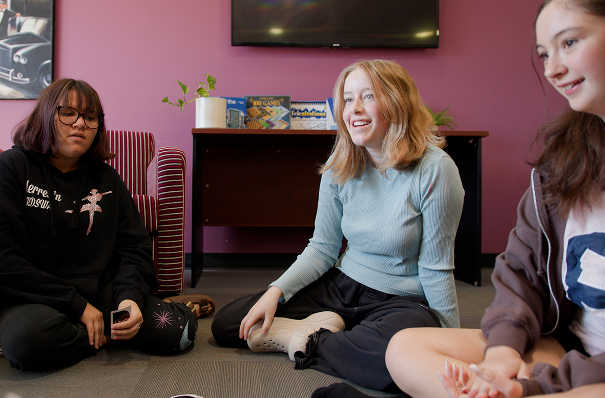 Merredin Residential College boarders sitting on the floor talking and smiling.