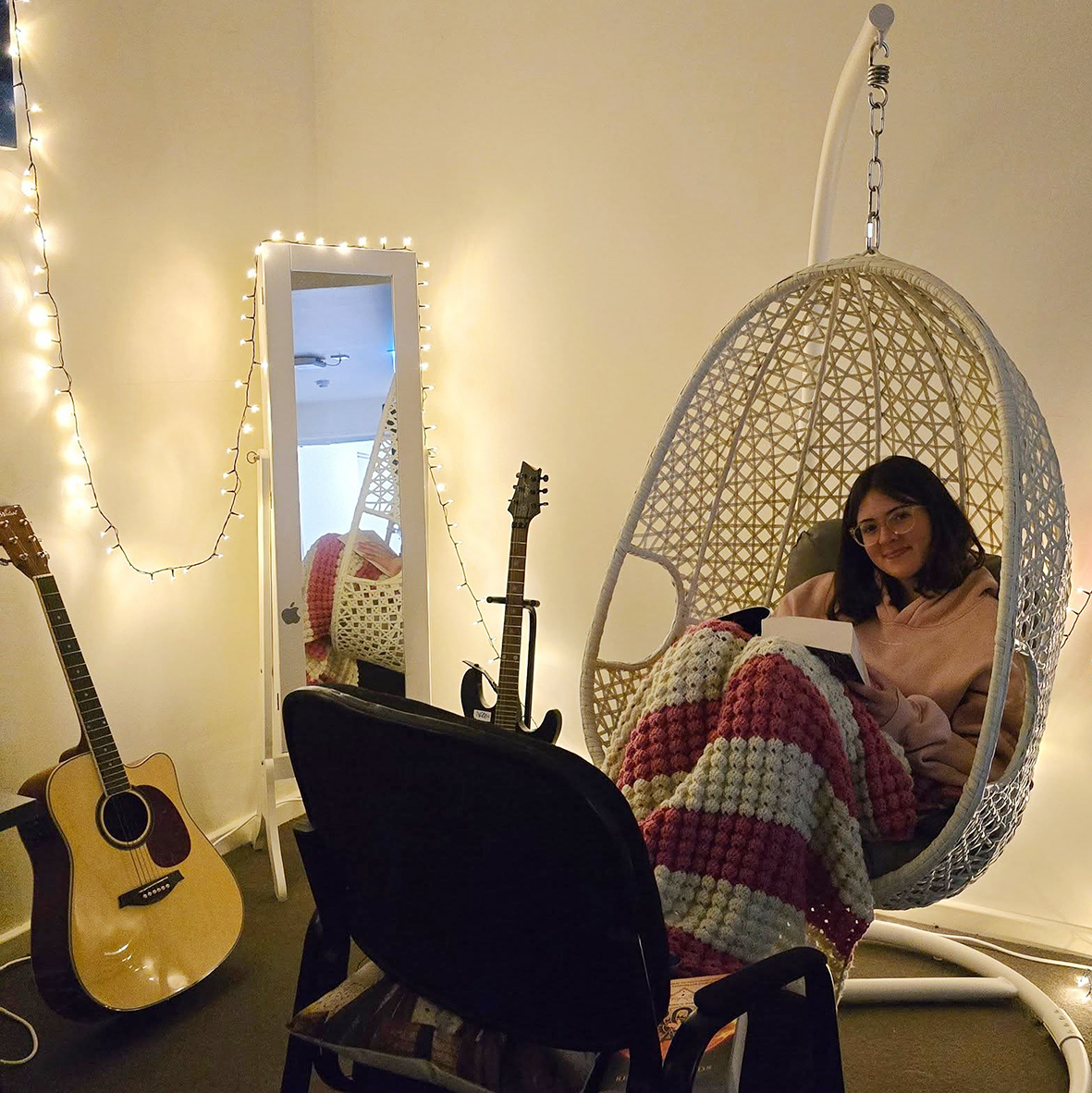 Boarder from Esperance Residential College sitting, reading a book in an egg chair with fairy light in the background.
