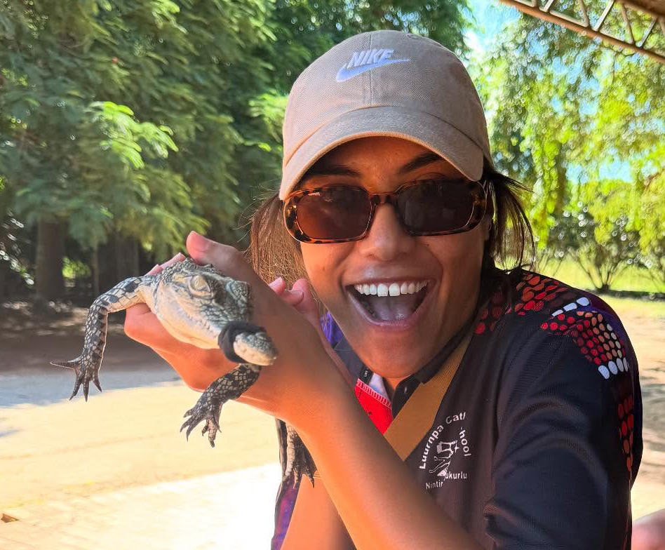 Broome Boarding Supervisor smiling while holding a baby crocodile.