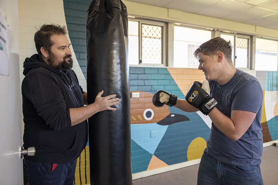 A Narrogin Residential College boarder using the punching bag in the college gym with a boarding supervisor.