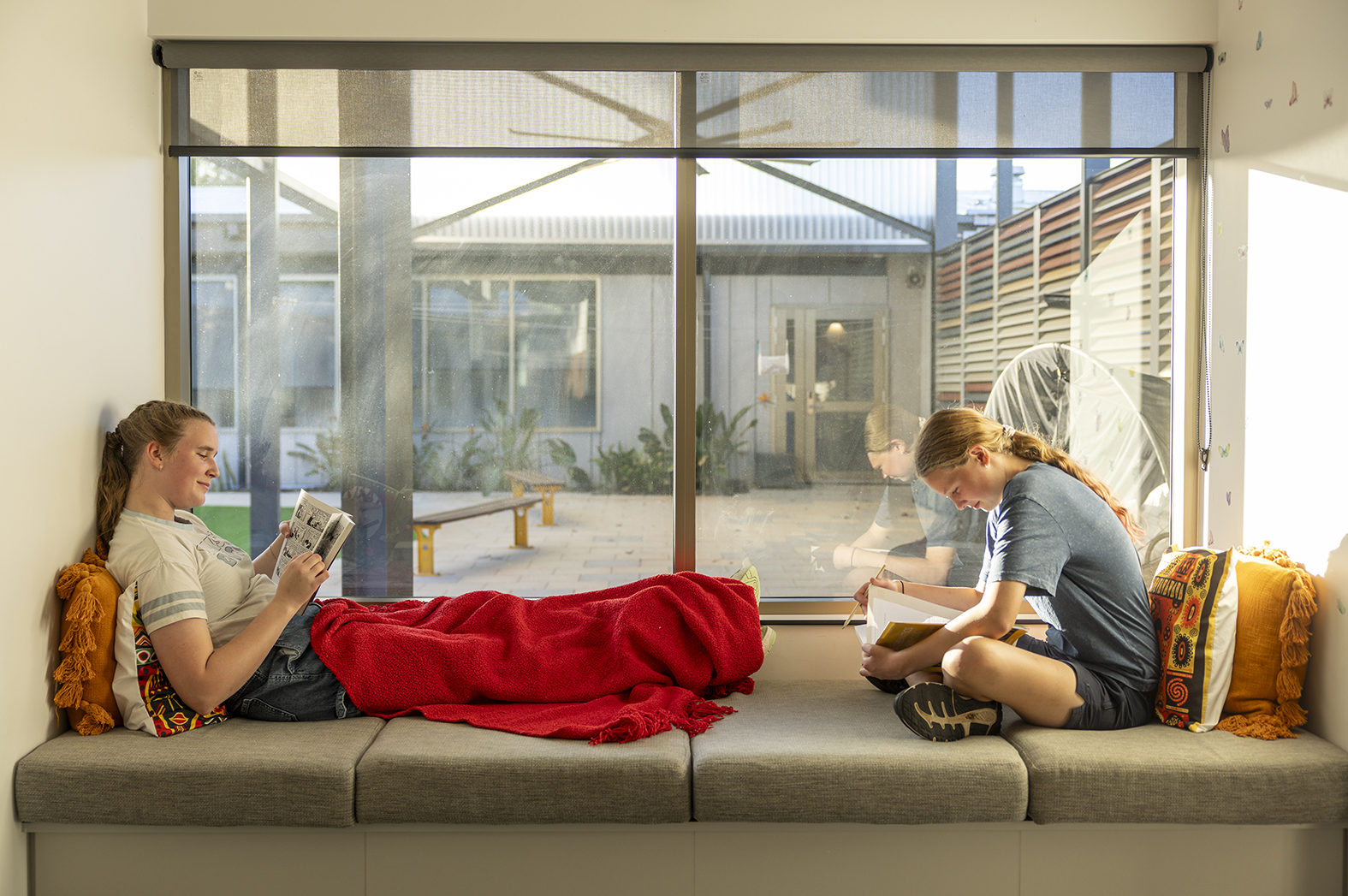 2 boarders from Moora Residential College reading by a big picture window.