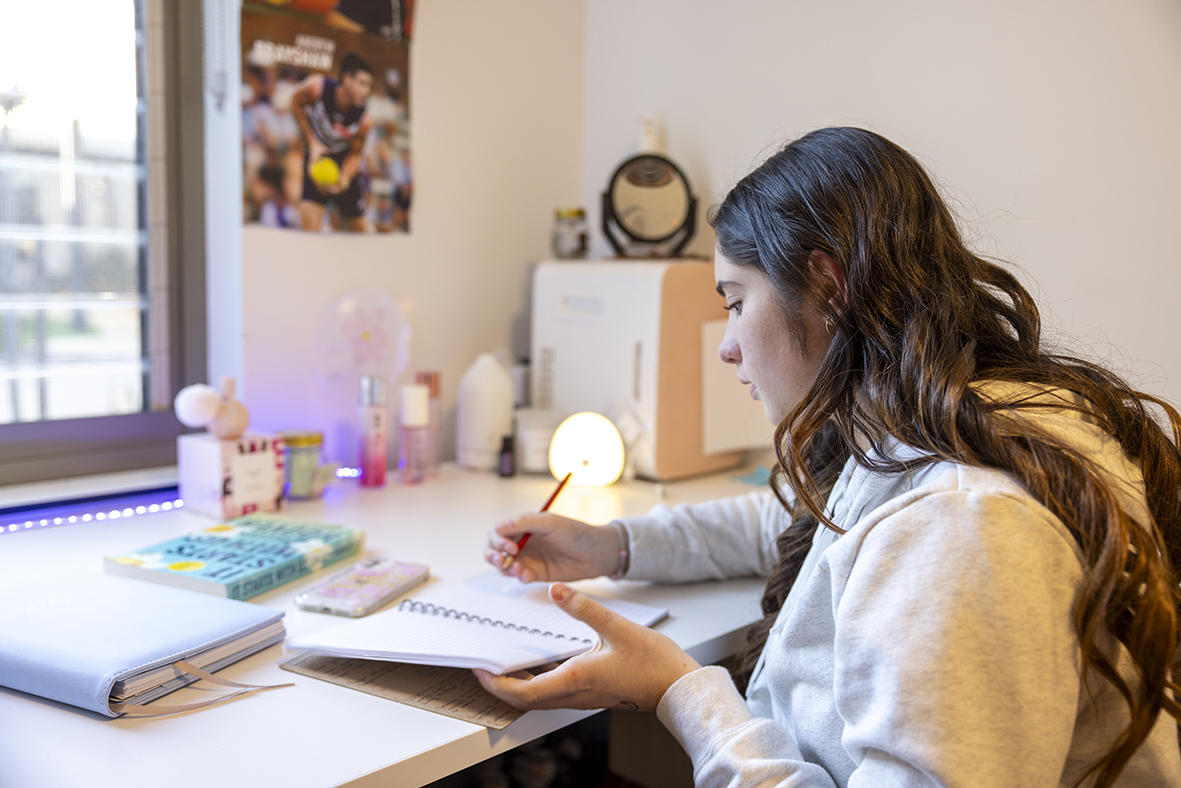 A Moora Residential College boarder sitting at the desk in her room.